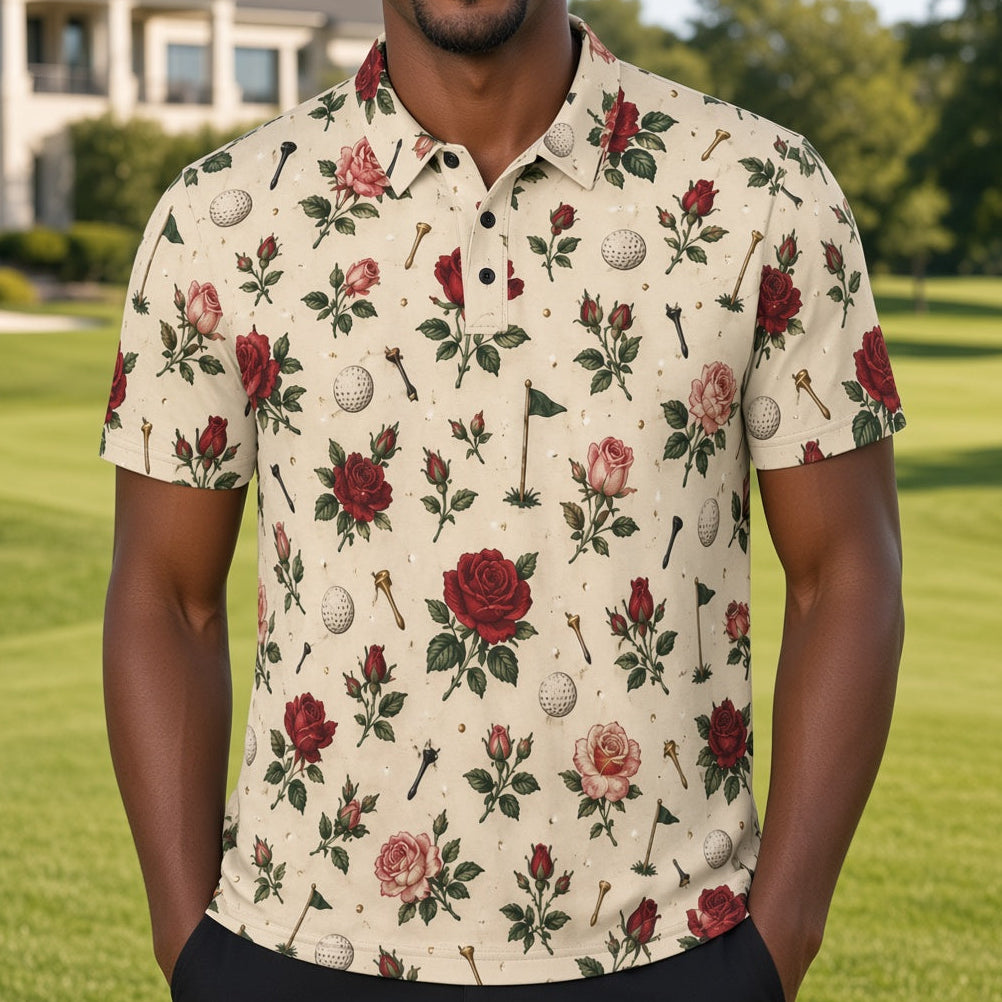 A man stands on a golf course wearing a short-sleeve button-up shirt with a beige base and a red, pink, and green floral and golf ball print, paired with black pants.
