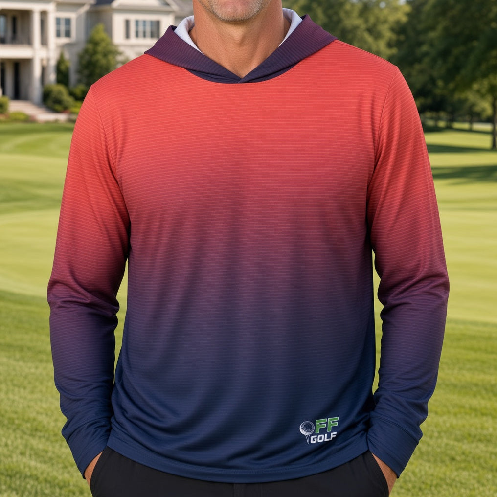 A man standing on a golf course wearing a long-sleeve hooded performance shirt with a red-to-blue gradient, with a large house in the background.