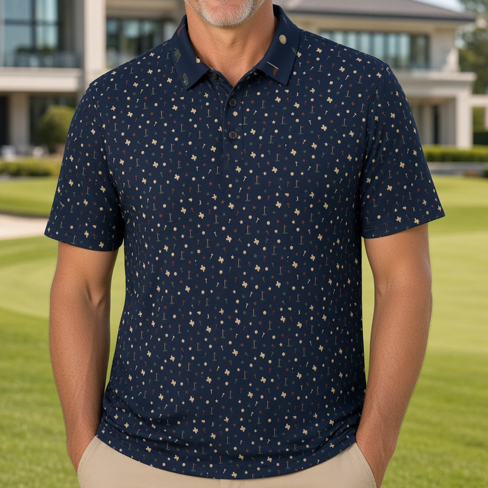 A smiling man stands on a manicured golf course wearing a navy blue short-sleeve polo shirt with a small beige star pattern, paired with khaki pants. A modern house is visible in the background.