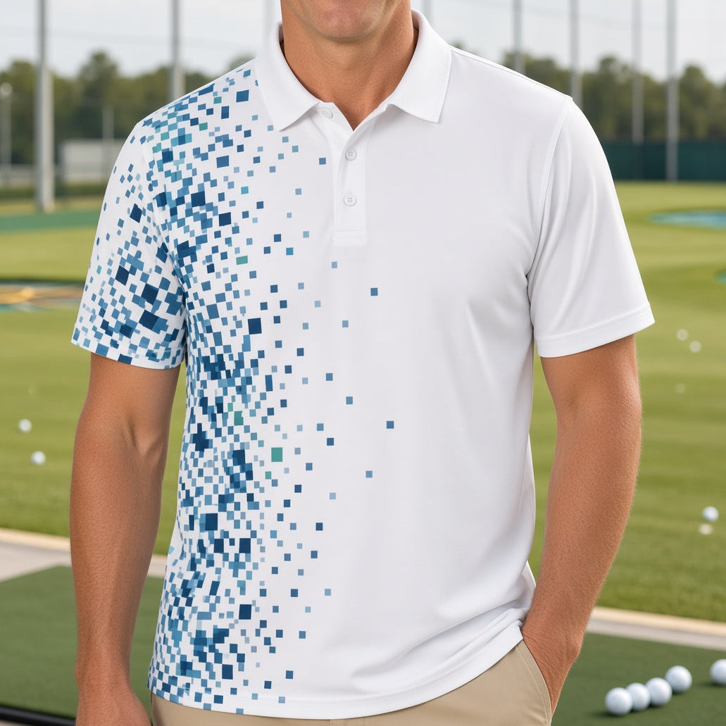 A man wearing a white short-sleeve polo shirt with a blue digital pixel pattern on the left side, standing on a golf driving range with golf balls and green grass in the background.