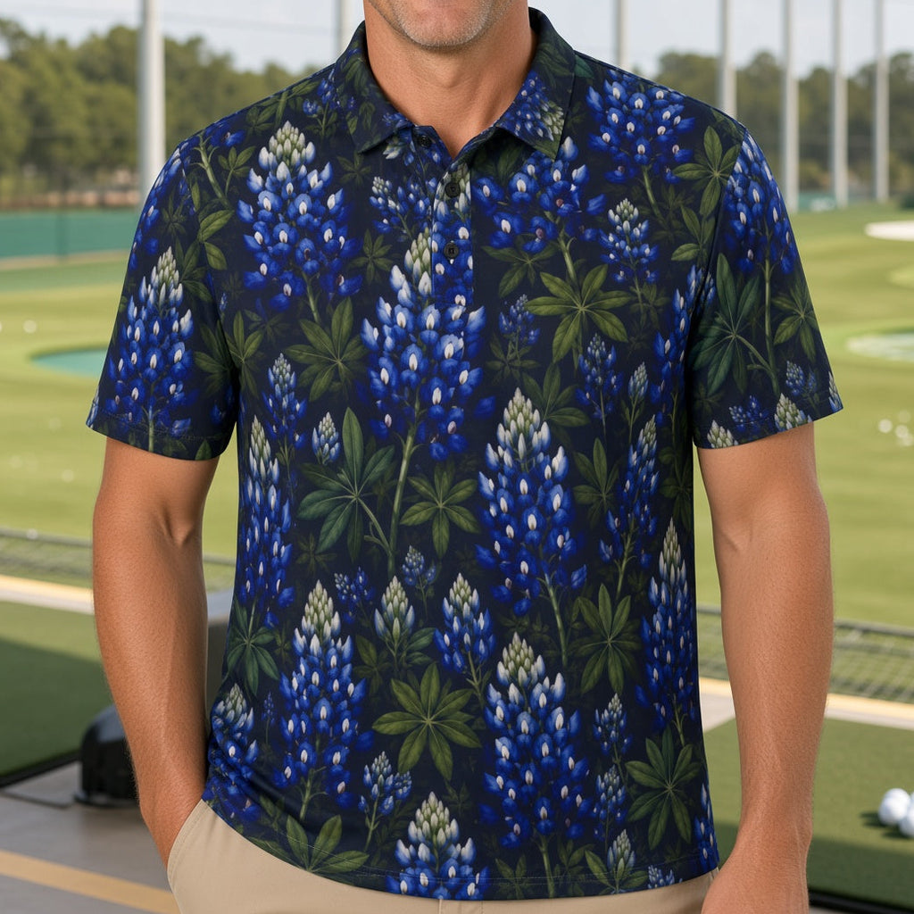 A man standing on a golf driving range wearing a short-sleeve polo shirt with a blue and green botanical print, paired with khaki pants.