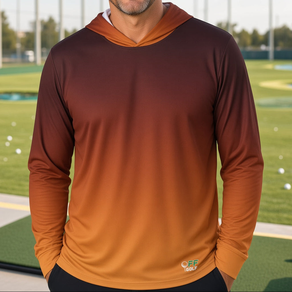 A man smiling on a golf driving range, wearing a long-sleeve hooded athletic shirt with a brown-to-orange gradient color transition.