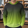 A man wearing a long-sleeve gradient hooded shirt with a black-to-green color transition, standing inside a retail store.