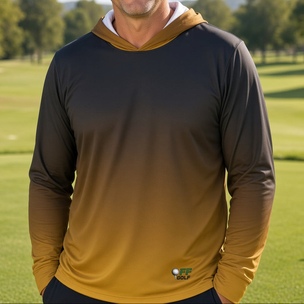 A smiling man wearing a long-sleeve gradient hoodie on a sunny golf course. The hoodie features a dark charcoal-to-golden-yellow color gradient, with a white inner hood lining and a small 'GOLF' logo near the bottom hem.
