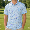 A smiling young man stands on a golf course wearing a light blue short-sleeve polo shirt with a blue and dark blue dotted pattern, paired with khaki pants.