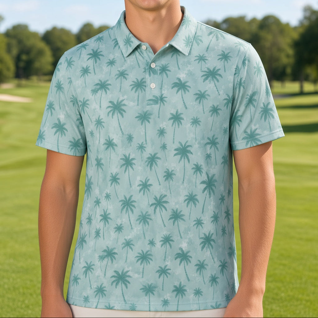 A smiling young man stands on a golf course wearing a light aqua short-sleeve polo shirt with an allover dark green palm tree pattern.
