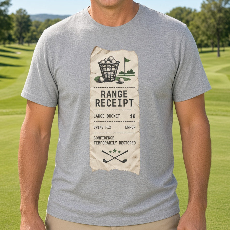 A smiling man wearing a light gray t-shirt with a vintage-style golf range receipt graphic, standing on a green golf course under a blue sky.