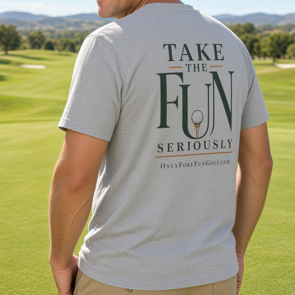 A man standing on a golf course wearing a light gray t-shirt with a dark green graphic on the back that reads 'TAKE THE FUN SERIOUSLY' and 'OnlyForFunGolf.com'.