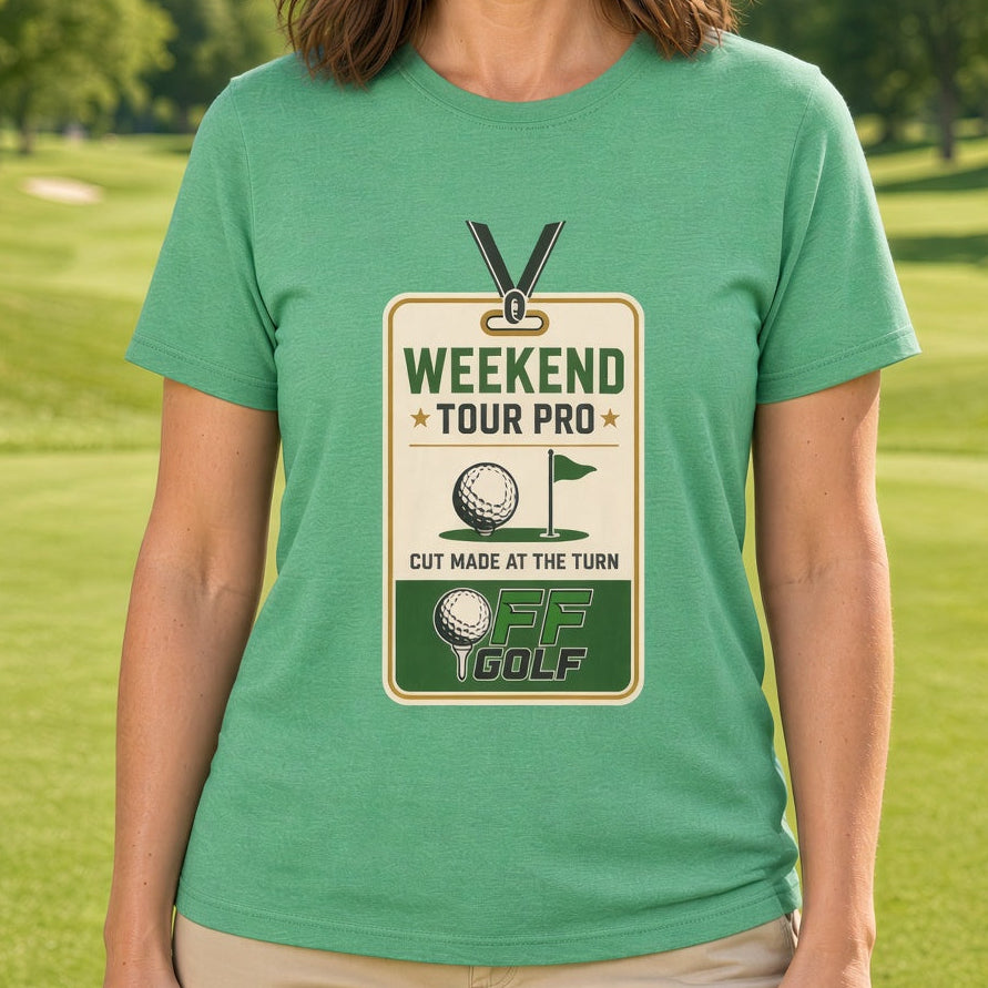 A woman stands on a golf course wearing a heather green graphic t-shirt that reads 'WEEKEND TOUR PRO' with a golf course badge design. The background shows a blurred green golf course under a blue sky.