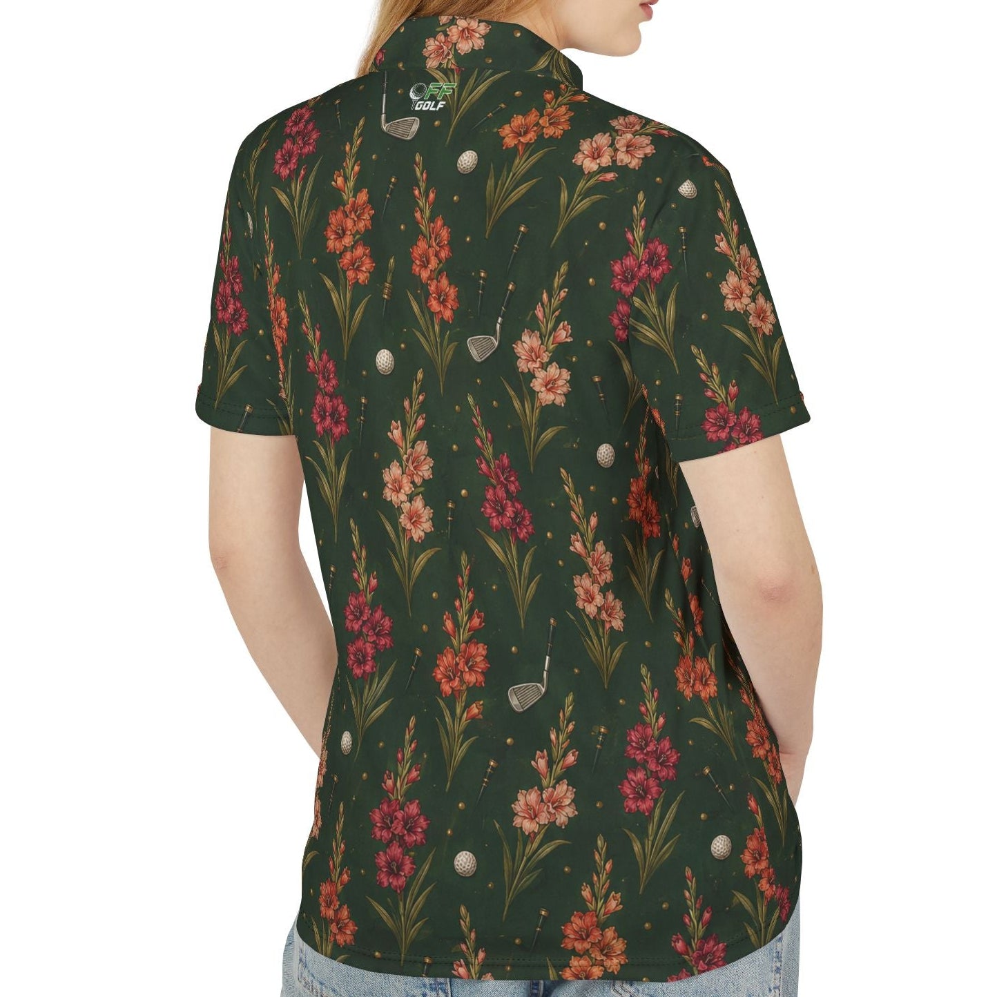 A woman shown from the back wearing a dark green short-sleeve button-up shirt with a colorful floral and bird pattern, paired with light blue jeans, against a plain white background.